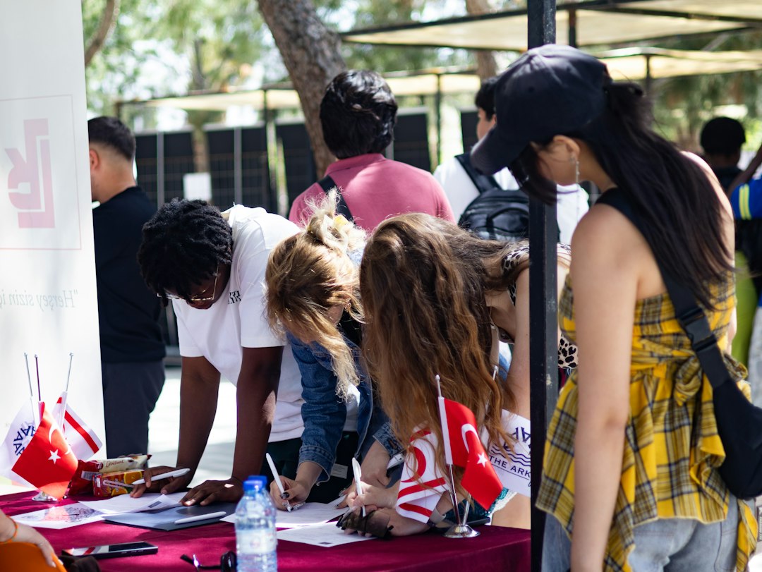 people-signing-papers-at-an-outdoor-table-with-flags-ipqz5hcx9ps